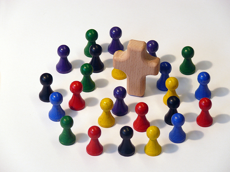 Bunte Holzfiguren um Kreuz versammelt